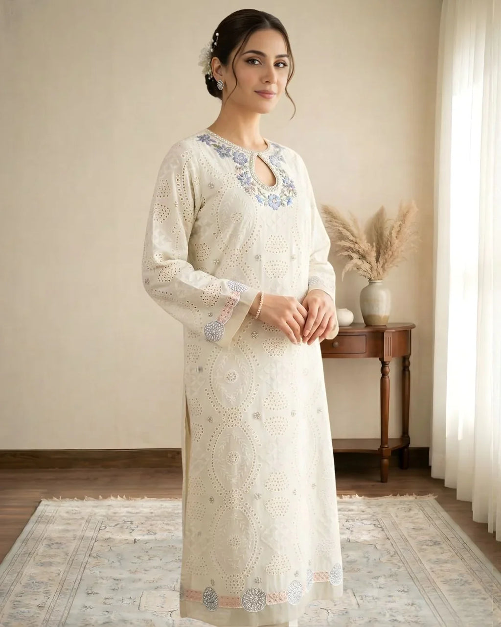 Woman in embroidered off-white kurta with blue floral neckline, standing in a bright room