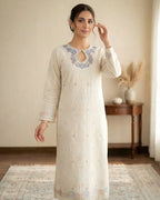Woman wearing an ivory embroidered kurta with floral neckline in a cozy indoor setting