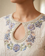 Close-up of a white embroidered women's kurta with floral patterns and pearl beaded neckline
