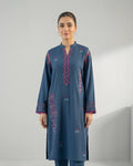 Woman wearing a blue embroidered kurta with pink and purple accents, standing indoors