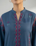 Woman wearing a blue embroidered kurta with magenta and teal detailing, close-up view