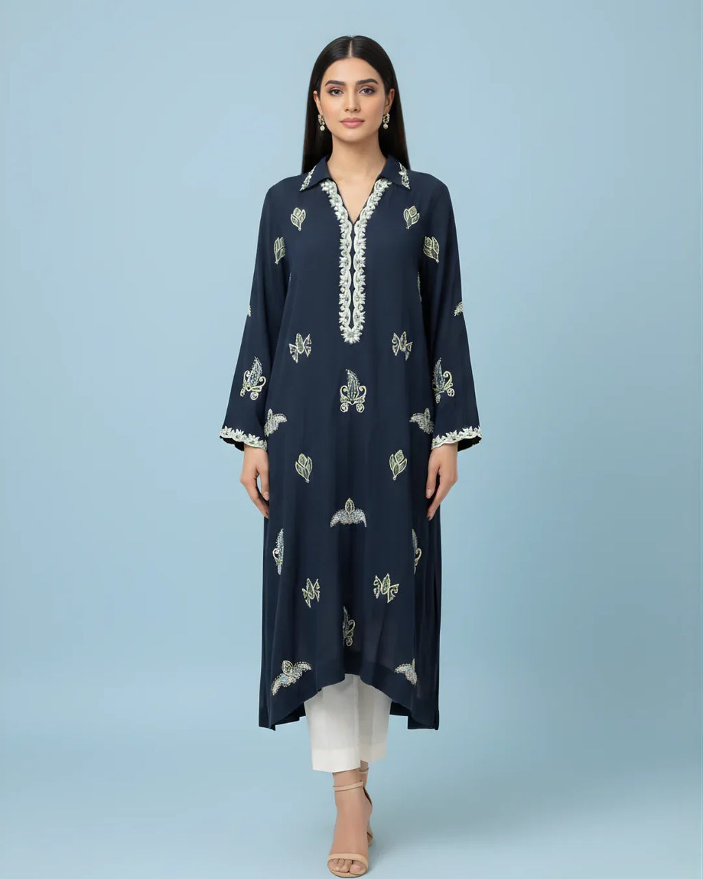 Woman wearing navy embroidered kurta with white trousers and beige heels on blue background