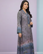 Woman wearing a grey and blue embroidered long kurta with floral patterns, standing against a pastel background