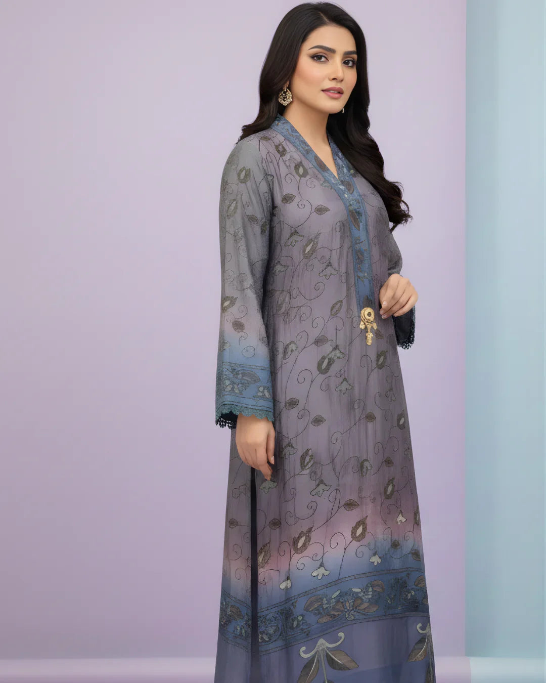 Woman wearing a grey and blue embroidered long kurta with floral patterns, standing against a pastel background