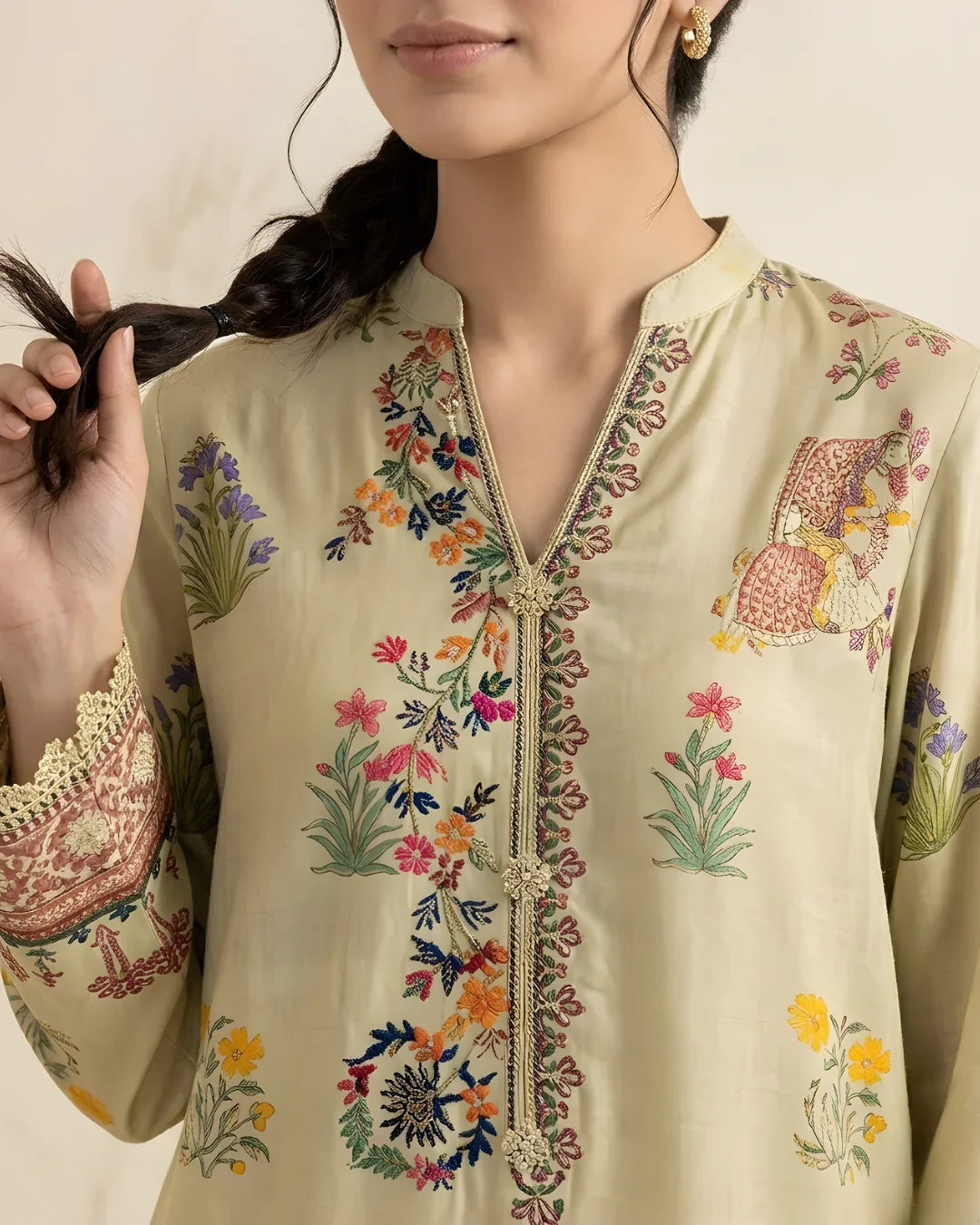 Close-up of a woman wearing a cream kurta with floral embroidery and ethnic motifs
